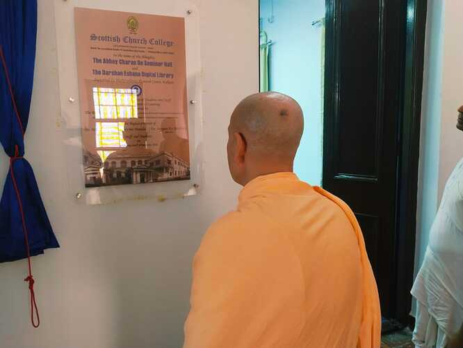 Radhanath-Swami-looks-at-the-entrance-plaque-of-the-Sri-Abhay-Charan-De-Seminar-Hall
